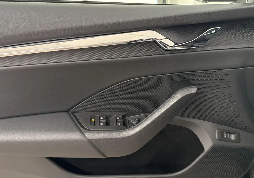 Intérieur de la porte côté conducteur d'une Skoda Octavia Combi gris graphite 2023, avec commandes des vitres et garniture texturée.