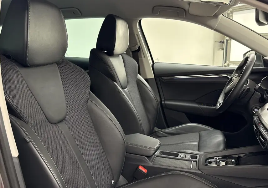 Intérieur de la Skoda Octavia Combi 2023 gris graphite, vue côté gauche sur sièges en cuir et tableau de bord moderne.
