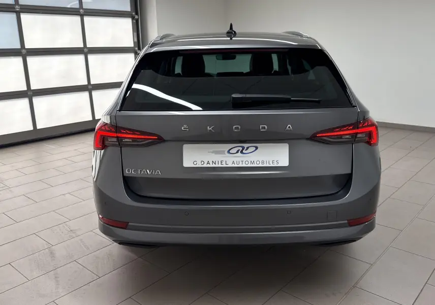 Vue arrière d'une Skoda Octavia Combi gris graphite 2023 avec feux LED et logo ŠKODA bien visibles.