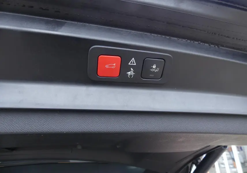 Boutons de commande du hayon motorisé avec accès mains libres sur le coffre d'un Peugeot 5008 noir métallisé, vue intérieure du hayon.