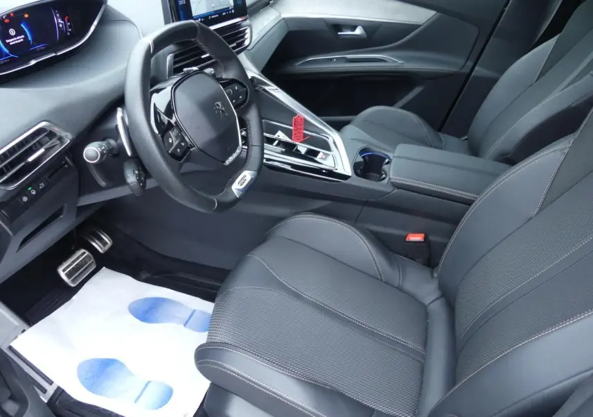 Vue intérieure côté conducteur du Peugeot 5008 GT 2023, avec sièges noirs et volant compact multifonctions cuir perforé.