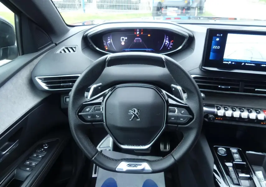 Vue intérieure centrée sur le volant cuir perforé GT et le combiné numérique du Peugeot 5008 noir métallisé 2023.