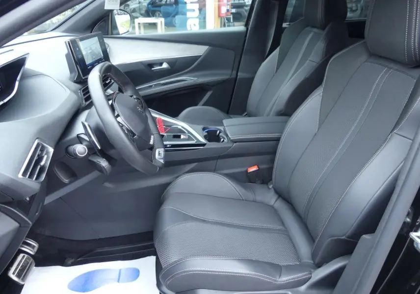 Intérieur avant droit du Peugeot 5008 GT 2023 noir métallisé avec sièges cuir noirs et volant compact multifonctions.