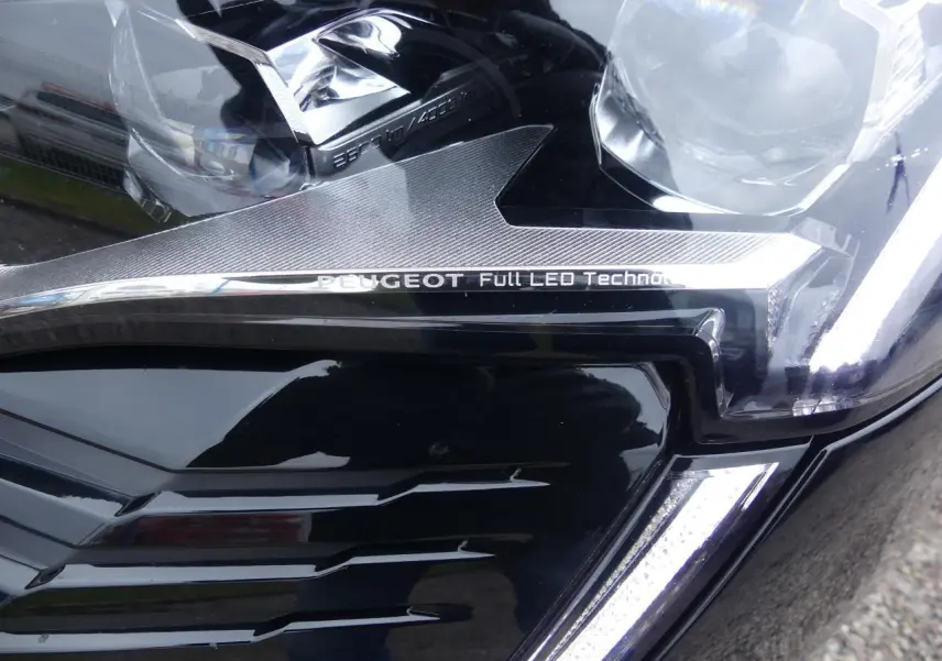 Gros plan sur le phare avant droit noir métallisé du Peugeot 5008 2023 avec signature Full LED et calandre GT chromée.
