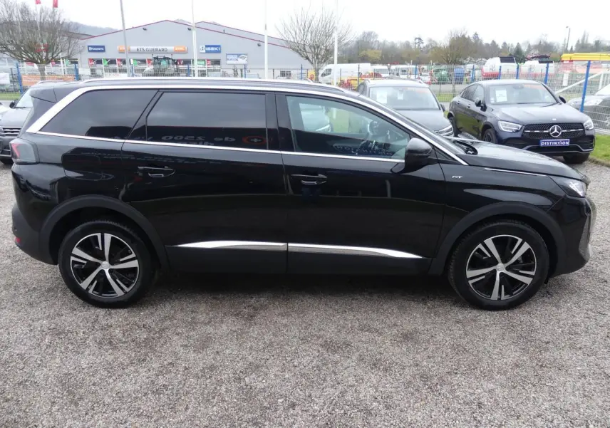 Profil côté droit du Peugeot 5008 GT 2023 noir métallisé avec jantes bi-ton et vitres arrière surteintées.