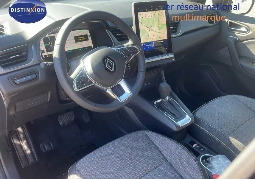 Intérieur du Renault Captur E-Tech hybride 2025 vu côté conducteur, volant multifonction et écran tactile central visibles.