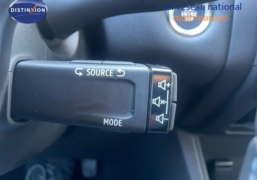 Gros plan sur la commande au volant du Renault Captur E-Tech hybride 2025, avec boutons source et mode visibles.
