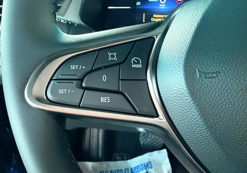 Gros plan sur les commandes au volant gauche du Renault Captur E-Tech hybride 2025, volant cuir noir.