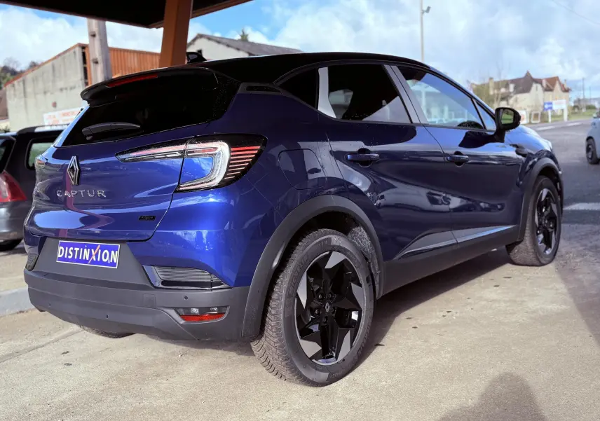 Renault Captur E-Tech hybride 2025 bleu Iron Metal avec toit noir, vue 3/4 arrière côté droit, jantes noires distinctives.