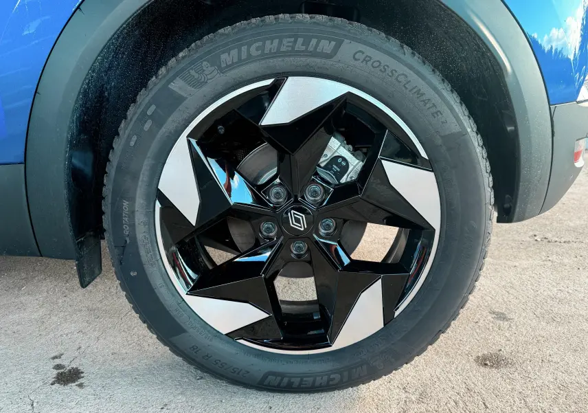 Gros plan sur la roue avant gauche du Renault Captur 2025 bleu Iron Metal avec jante noire et argentée au design géométrique.