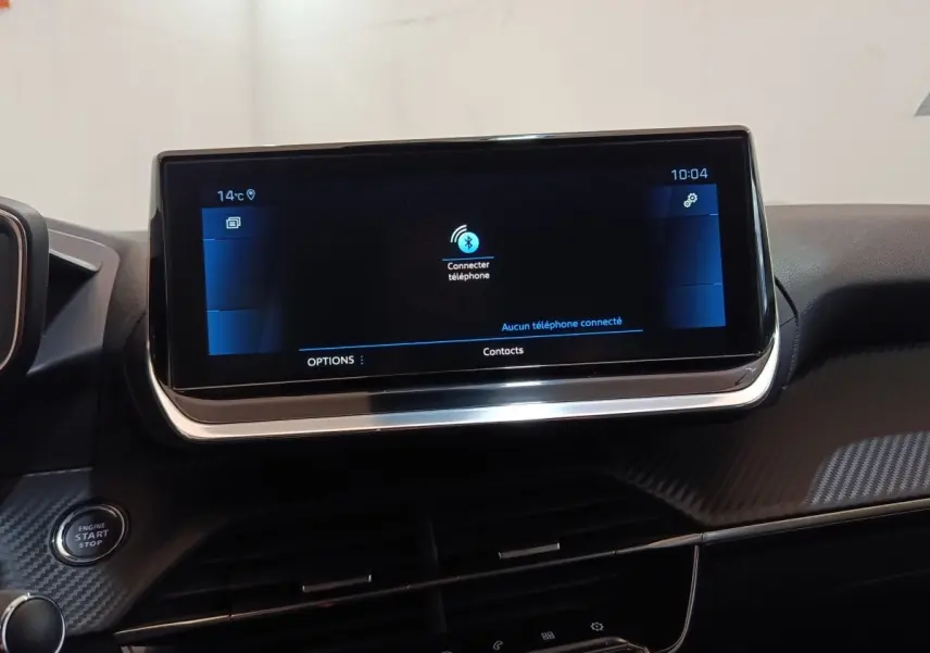 Écran tactile central allumé vu de face dans l’habitacle noir d’une Peugeot 208 blanche PureTech 2021.