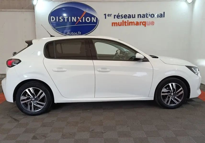Vue de profil côté gauche d'une Peugeot 208 blanche PureTech 100 S&S Allure Business avec jantes alliage et vitres teintées.