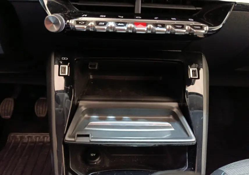 Vue rapprochée de la console centrale noire du Peugeot 208 blanc, avec ports USB et commandes en rangée chromée.