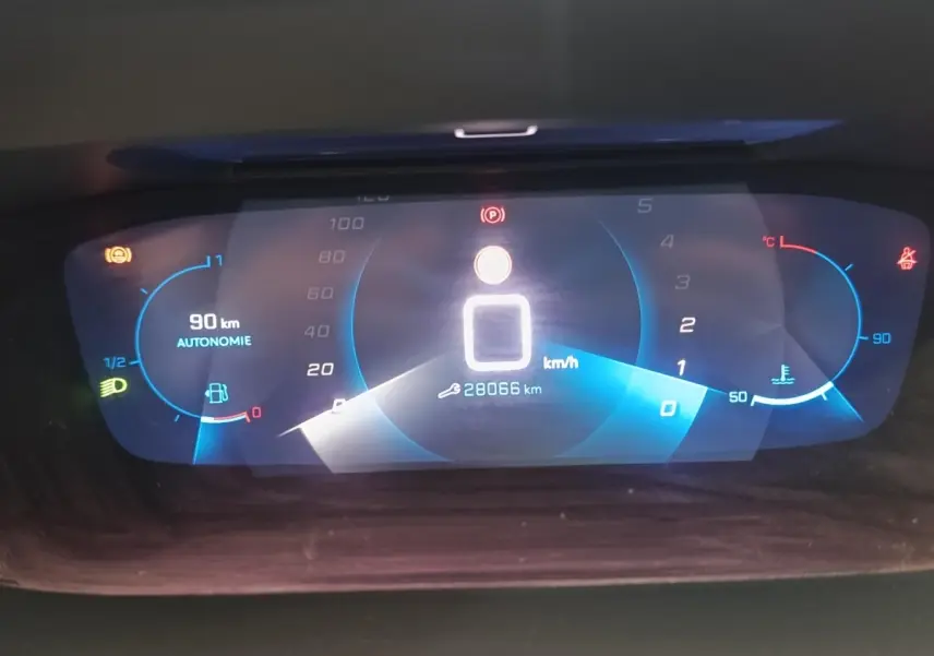 Affichage numérique du tableau de bord de la Peugeot 208 blanc, montrant la vitesse à 0 km/h et l'autonomie à 90 km.