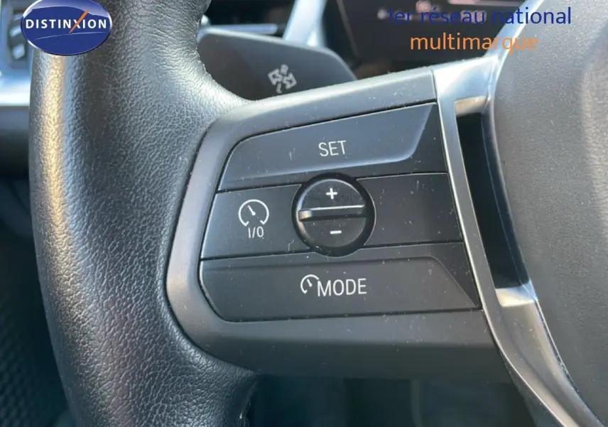 Gros plan sur les commandes de régulateur de vitesse au volant d’une BMW Série 2 Active Tourer 218i bleu phytonique.