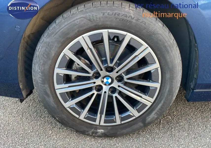 Gros plan sur la roue avant gauche d'une BMW Série 2 Active Tourer bleu phytonique avec jante alliage multibranches.