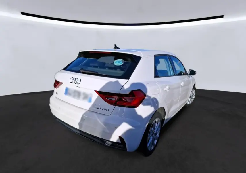 Vue 3/4 arrière droite d'une Audi A1 blanche 2022 avec jantes alu 17 pouces et feux arrière LED dans un garage.