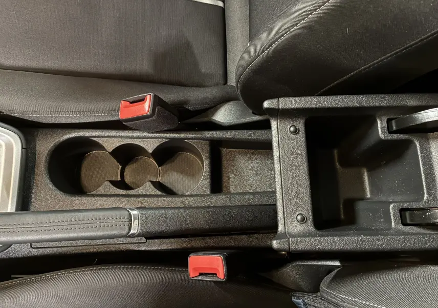 Vue rapprochée de la console centrale noire avec porte-gobelets et frein à main sur Audi A1 blanche 2022.