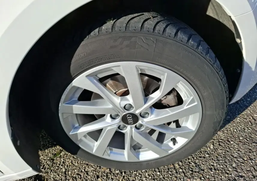 Vue 3/4 arrière droite d'une Audi A1 blanche avec jantes alu 17 pouces, garée en intérieur sur sol béton.