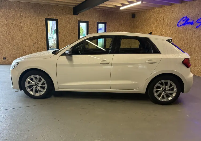 Audi A1 blanche vue de profil côté gauche, avec jantes alu 17 pouces dans un garage intérieur.