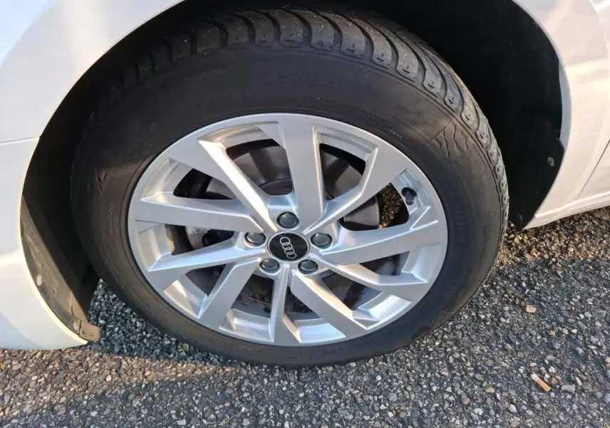 Gros plan sur la roue avant gauche d'une Audi A1 blanche avec jante alu 17 pouces au design moderne.