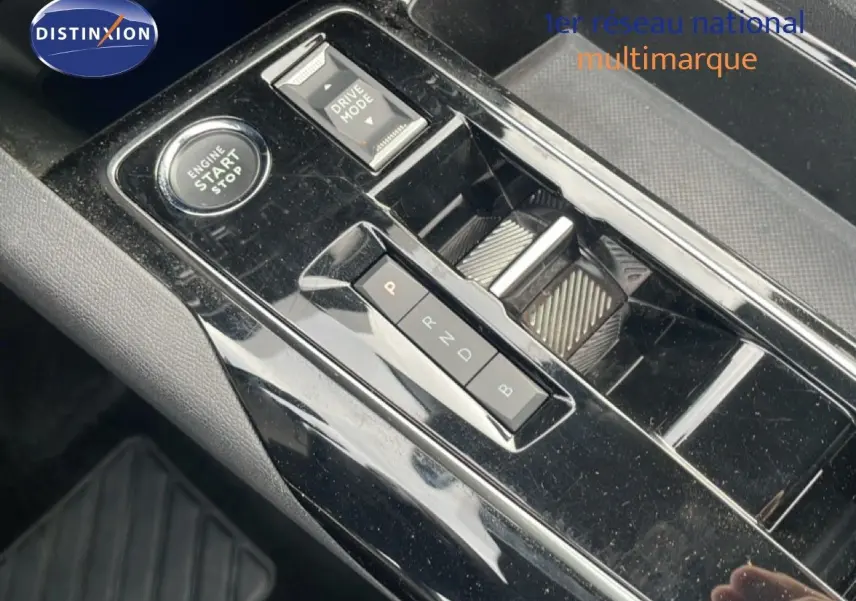 Gros plan sur la console centrale noire brillante du Peugeot 3008 hybride 2024 avec bouton start/stop et commandes de boîte auto.