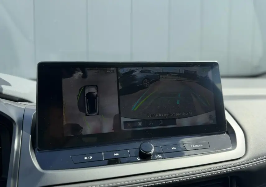 Écran tactile intérieur du Nissan Qashqai 2025 affichant la caméra de recul et la vision 360°, avec tableau de bord gris.