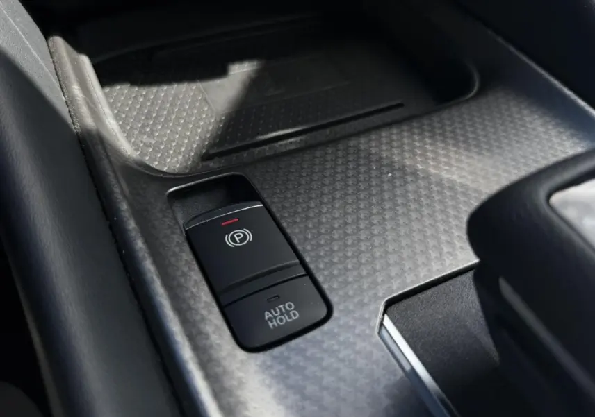 Gros plan sur la commande de frein à main électrique et fonction Auto Hold dans le console centrale du Nissan Qashqai blanc nacré.
