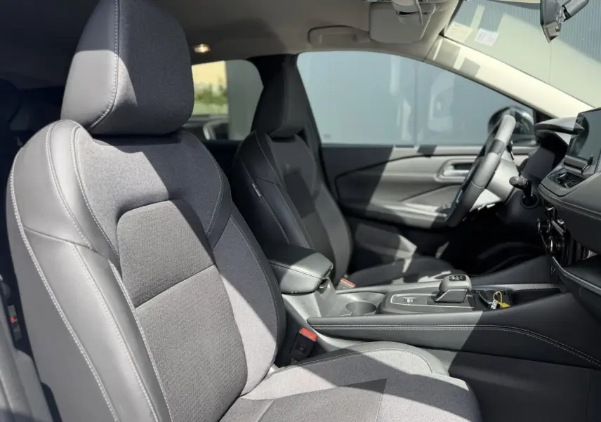 Vue intérieure côté gauche du Nissan Qashqai 2025, sièges avant en tissu et TEP noir avec surpiqûres blanches.