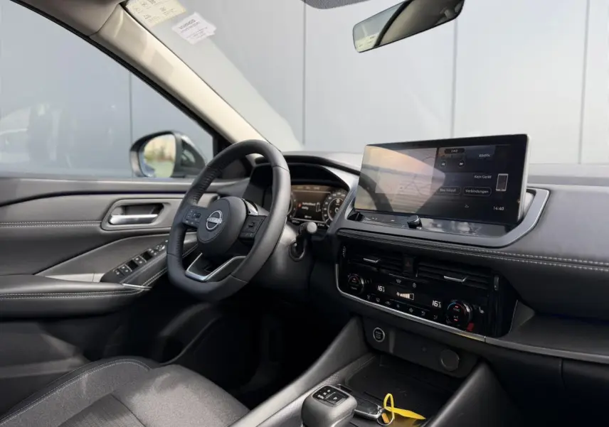 Intérieur côté conducteur du Nissan Qashqai 2025 avec tableau de bord noir, écran tactile et volant cuir multifonction.