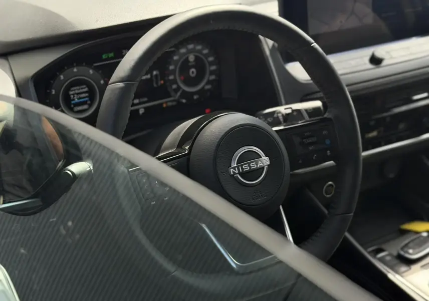 Vue rapprochée du volant noir et du tableau de bord numérique du Nissan Qashqai 2025, intérieur moderne et épuré.