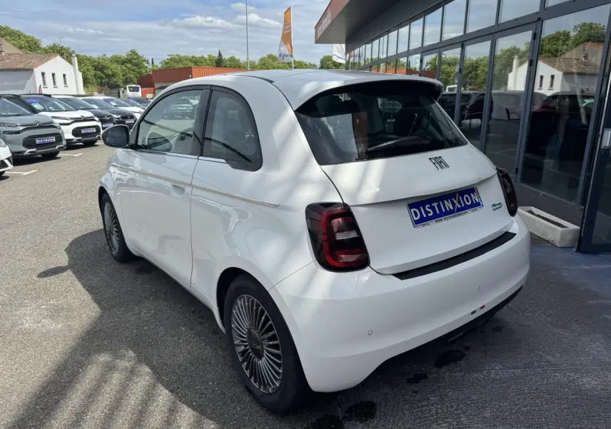 Vue 3/4 arrière droite d'une Fiat 500 électrique blanche avec jantes alliage 16'' et toit panoramique.
