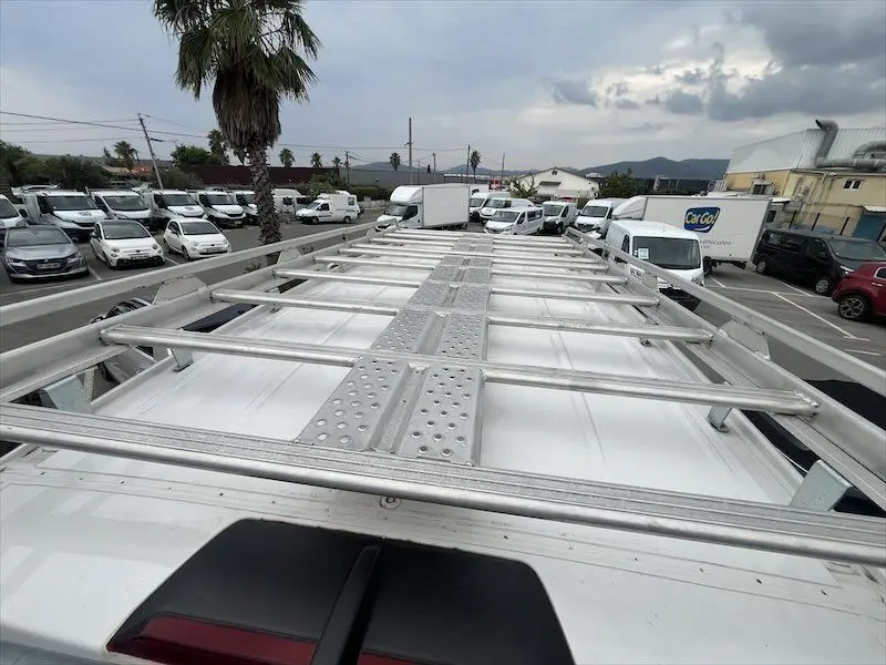 Vue en plongée sur la galerie métallique du toit d’un Volkswagen Crafter blanc stationné en extérieur.