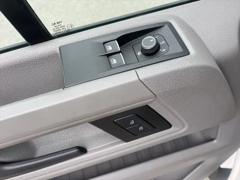 Gros plan sur la commande des vitres et rétroviseurs côté conducteur du Volkswagen Crafter blanc de 2019.