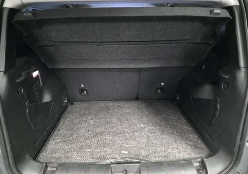 Coffre ouvert vu de l'arrière du Jeep Renegade gris, montrant le plancher modulable et les côtés noirs.