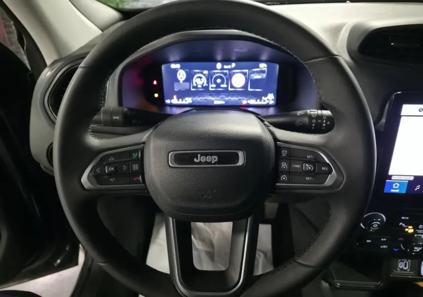 Vue rapprochée du volant Jeep Renegade 2024 avec commandes intégrées et tableau de bord numérique lumineux.