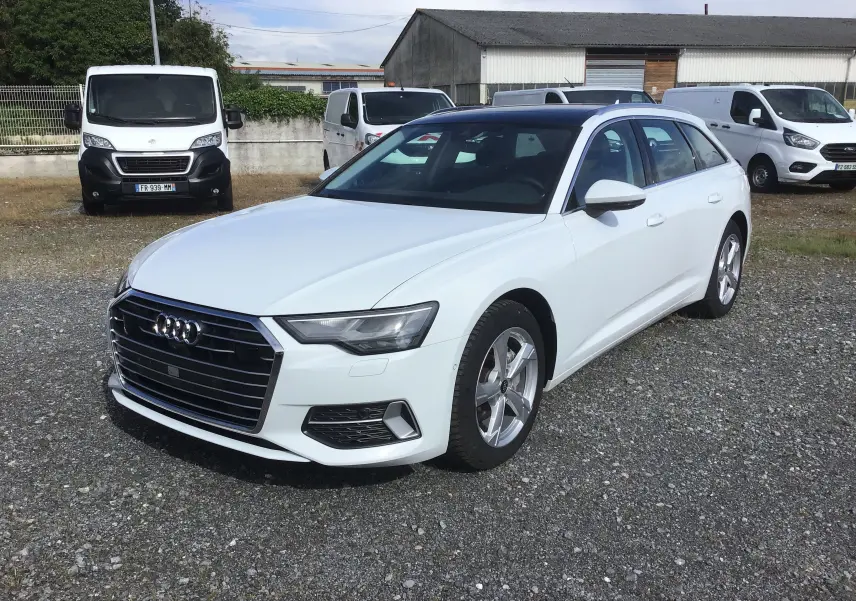 Audi A6 Avant blanc glacier vue 3/4 avant droit sur parking avec toit noir contrasté et jantes alliage.