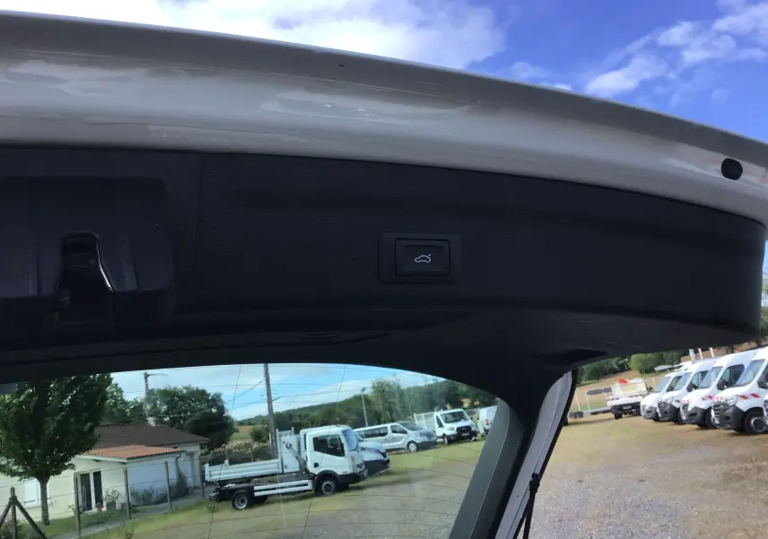 Bouton d'ouverture électrique du hayon sur la partie intérieure du coffre d'une Audi A6 Avant blanc glacier, vue de l'arrière ouvert.