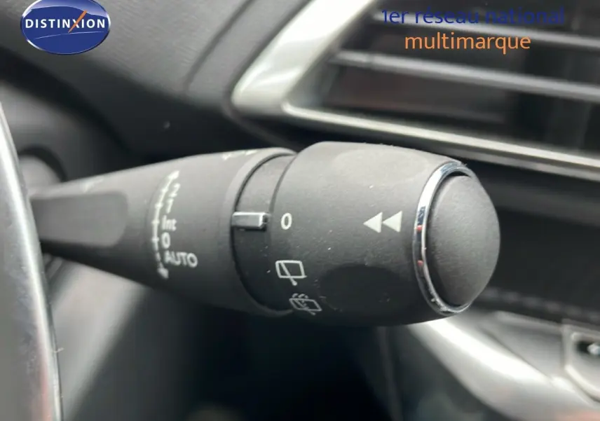 Gros plan sur la commande d’essuie-glace à gauche du volant dans l’habitacle noir du Peugeot 3008 hybride gris Artense 2024.