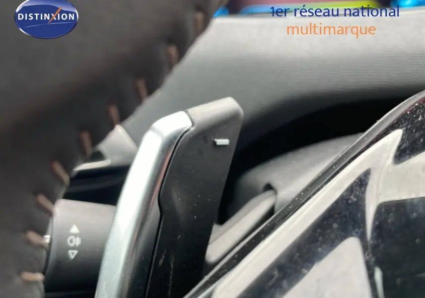 Gros plan sur la palette de changement de vitesse derrière le volant du Peugeot 3008 gris Artense 2024 hybride rechargeable.