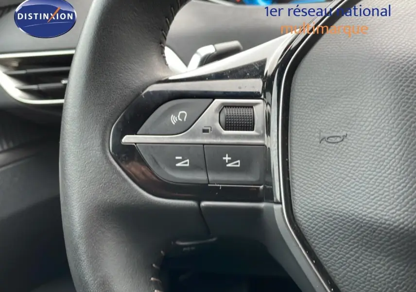Gros plan sur les commandes gauche du volant noir du Peugeot 3008 hybride rechargeable 2024, avec boutons de réglage et molette.