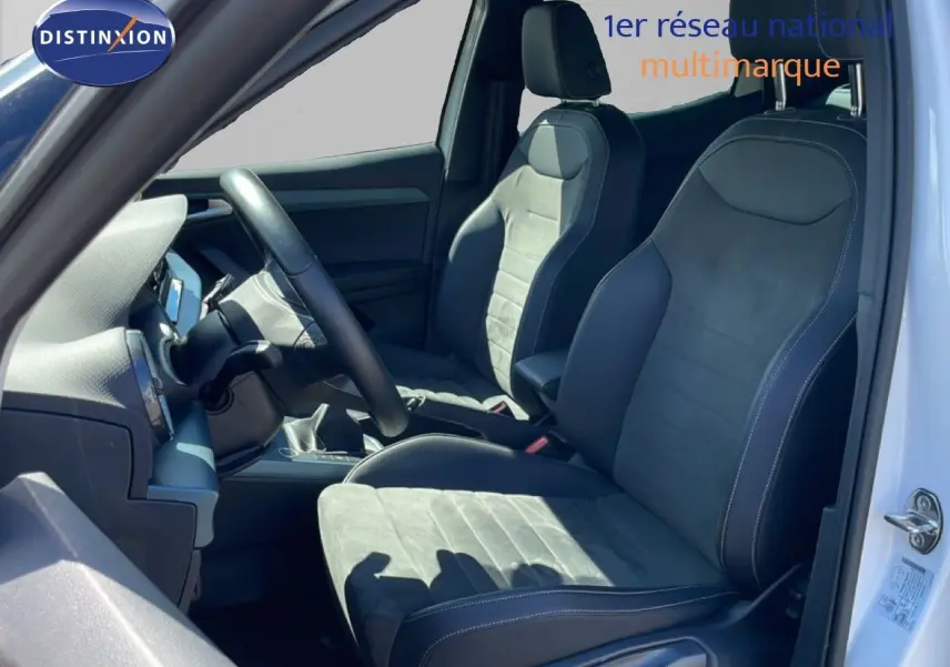 Vue intérieure côté conducteur du SEAT Arona blanc alpin avec sièges en cuir et alcantara noirs, volant multifonction visible.