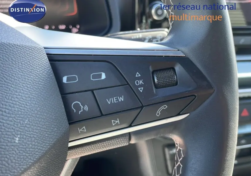Gros plan sur les commandes multifonctions à droite du volant cuir noir du SEAT Arona blanc alpin 2025.