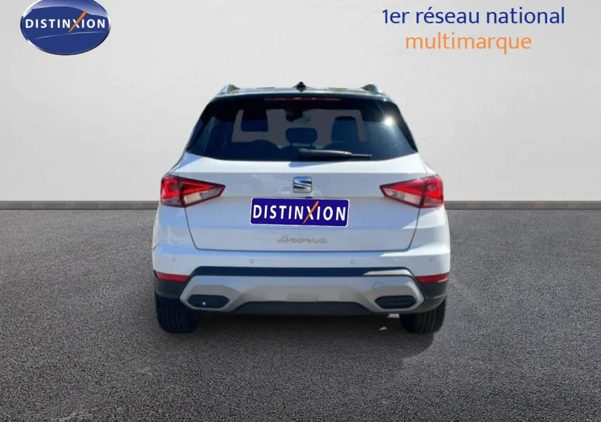 Vue arrière d'un SEAT Arona blanc alpin avec toit noir, feux arrière LED et double sortie d'échappement intégrée.