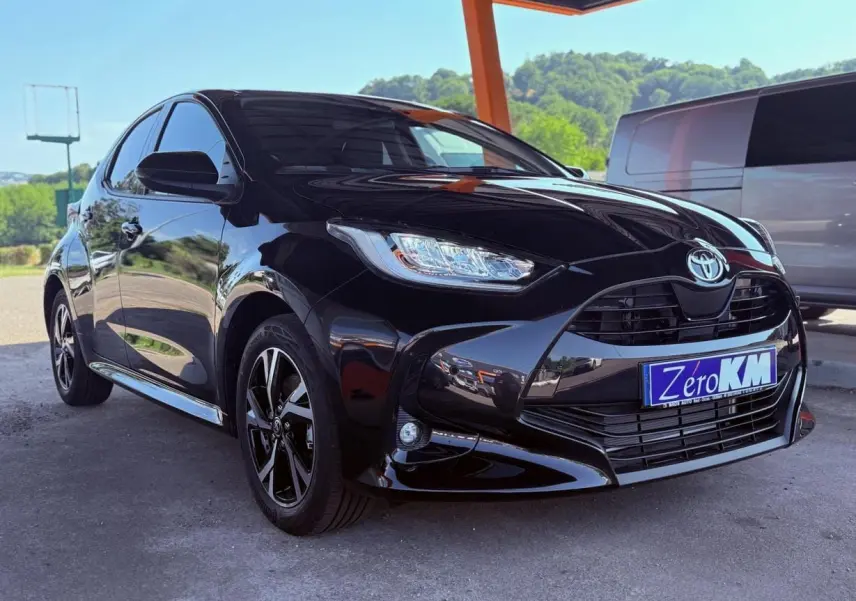 Toyota Yaris Hybrid noire vue en 3/4 avant gauche sous un abri avec jantes noires et phares LED.