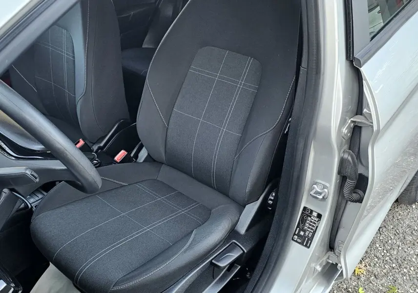 Vue intérieure côté conducteur de la Ford Fiesta gris lunaire, mettant en valeur le siège tissu noir à motifs gris et le volant.