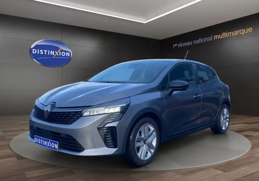 Renault Clio V E-Tech gris schiste vue 3/4 avant droit, projecteurs LED allumés en showroom.