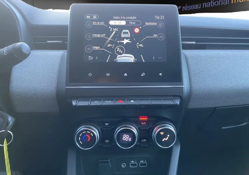 Vue intérieure du tableau de bord de la Renault Clio V E-Tech gris schiste, avec écran tactile et commandes climatisation.