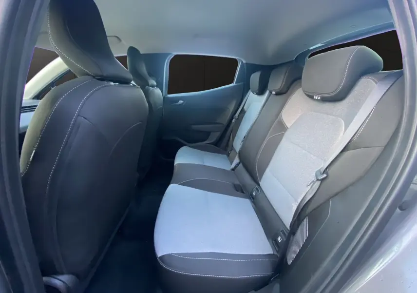 Vue intérieure arrière droite de la Renault Clio V E-Tech gris schiste, montrant la banquette arrière en tissu gris et noir.