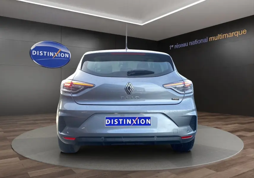Vue arrière d'une Renault Clio V E-Tech Full Hybrid gris schiste avec feux LED allumés en intérieur showroom.